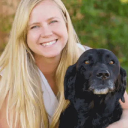 Morgan Domangue smiling and posing with a black dog